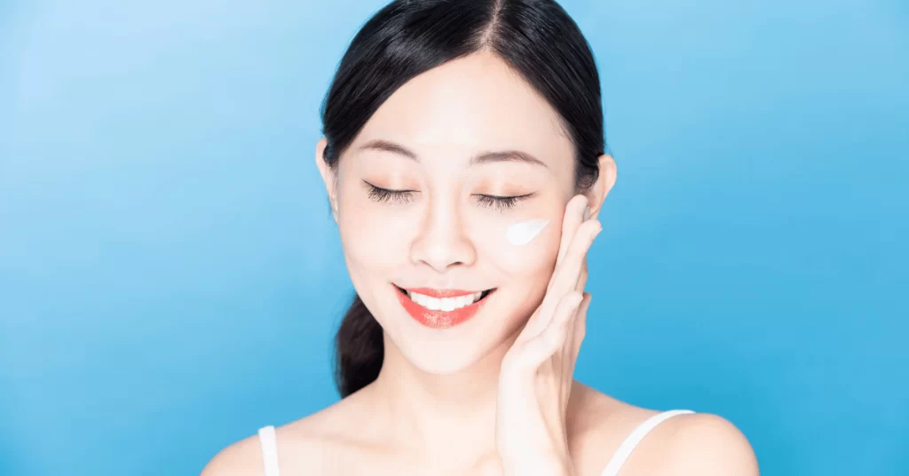 Asian woman applying sunscreen